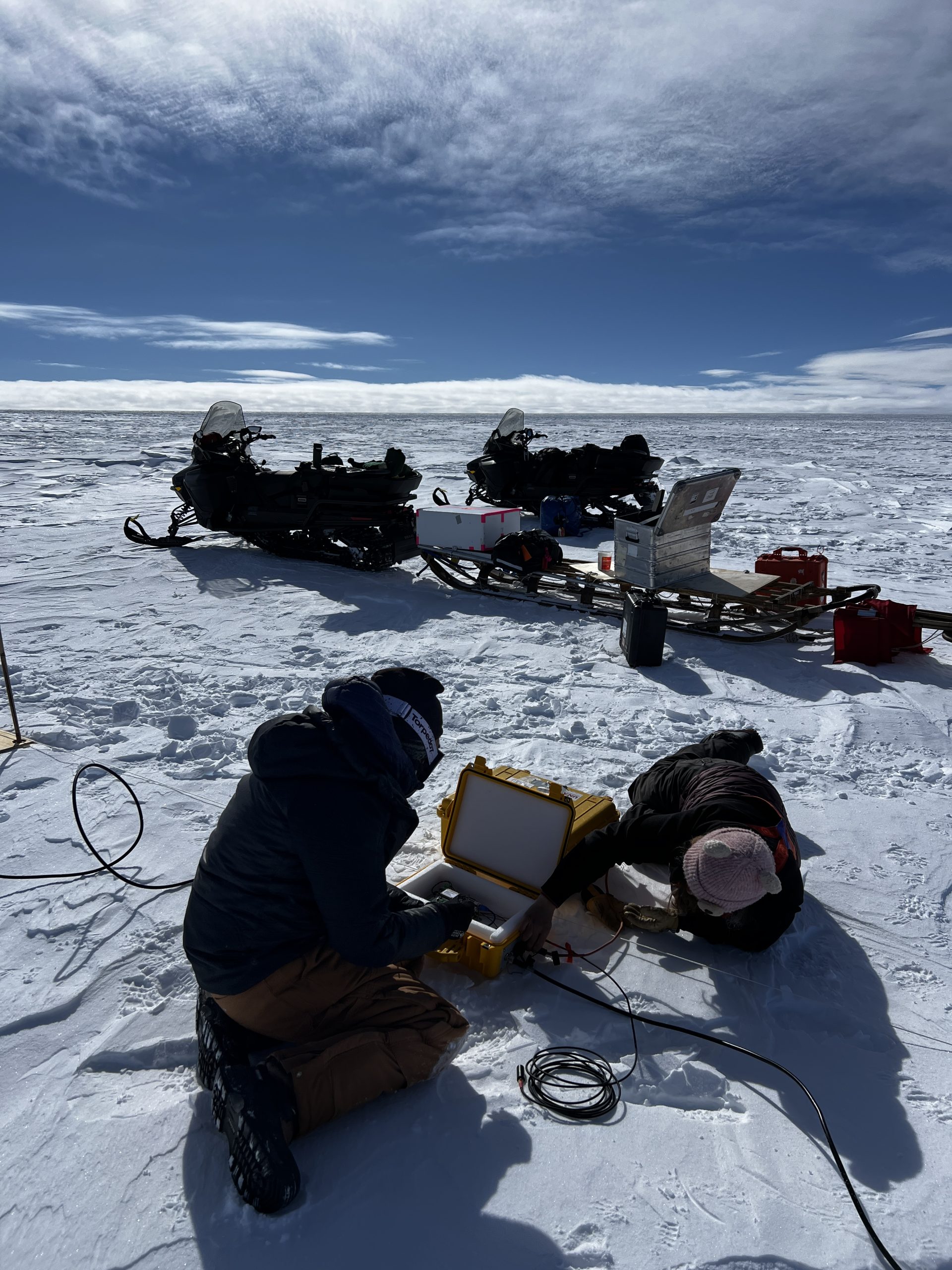 Zoe plugging wires into the ApRES computer and Ellen inserting SD cards